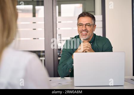 Lächelnder älterer Geschäftsmann unterhält sich im Gespräch mit dem Büro. Stockfoto