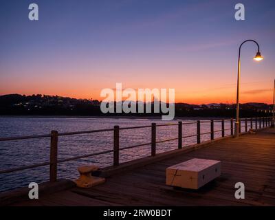 Orangefarbener Himmel, Coffs Harbour Jetty mit Blick über das Wasser bei Sonnenuntergang Stockfoto