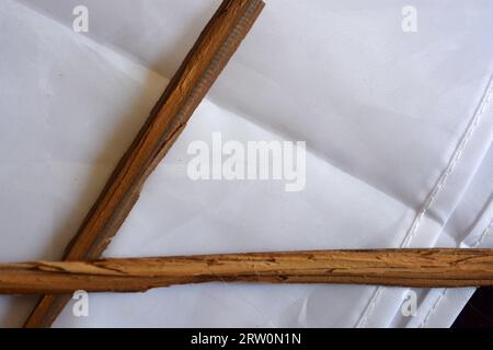 Ungewöhnliche Dinge, zwei braune Holzstöcke, lange Splitter von Holzmöbeln liegen chaotisch auf weißem mattem Stoff. Stockfoto