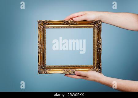 Mann, der einen goldenen Rahmen im antiken Stil in den Händen hält Stockfoto