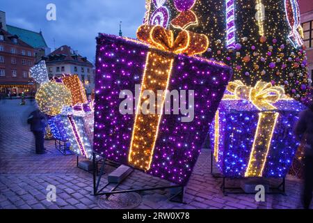 Beleuchtete Weihnachtsgeschenke, Geschenke unter dem Weihnachtsbaum, Weihnachtsbeleuchtung im Freien, dekorative Beleuchtung am Abend Stockfoto