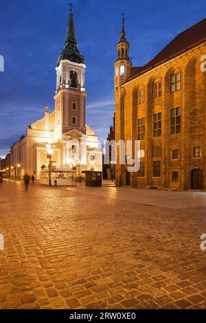 Kirche des Heiligen Geistes und altes Rathaus auf dem Marktplatz bei Nacht in Torun, Polen Stockfoto