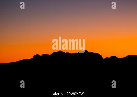 Die Silhouette der Felsbrocken der Olgas bei Sonnenuntergang an einem klaren Winter #39, s Abend im Northern Territory, Australien Stockfoto