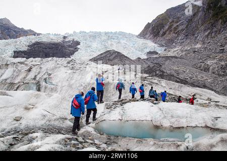 Franz Josef, Neuseeland, 22. März 2015: Eine Gruppe von Touristen, die auf dem Franz-Josef-Gletscher in Richtung eines Hubschraubers wandern Stockfoto