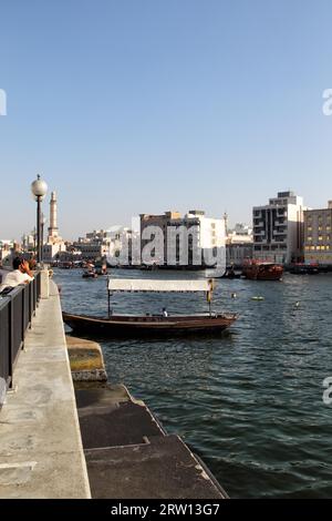 Blick über den Dubai Creek von Deira nach Bur Dubai. Abras, die typischen Wassertaxis in Dubai, fahren auf dem Fluss. Das Minarett der Großen Moschee Stockfoto