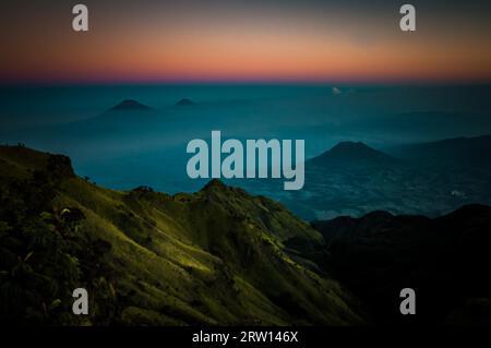 Panoramabild des ruhenden Stratovulkans, des Mount Merbabu und der umliegenden Berge, bedeckt mit Nebel während des Sonnenaufgangs in der Nähe von Yogya in Zentral-Java Stockfoto