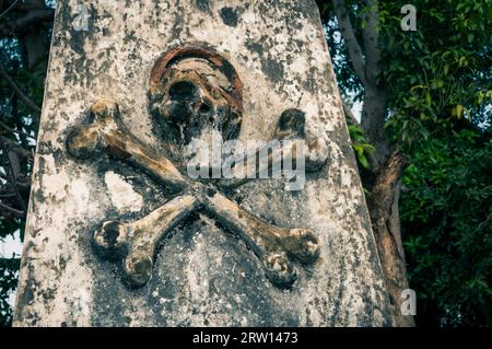 Foto von Steinsäule mit Symbol des Todes, Schädel und Knochen auf dem Friedhof in Surabaya in der Provinz Java, Indonesien Stockfoto