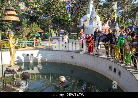 Kathmandu, Nepal, 20. Oktober 2014: Menschen werfen Münzen in einen Wunschbrunnen in Swayambhunath Stupa Stockfoto