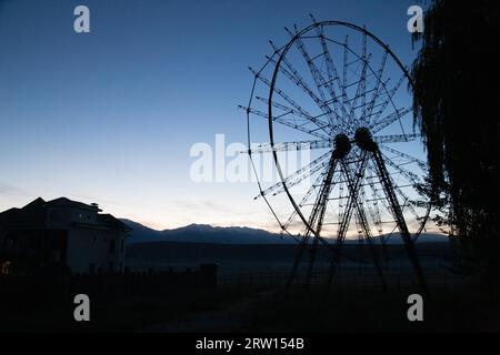 Die Silhouette eines alten, verlassenen Riesenrades in Toktogul, Kirgisistan Stockfoto