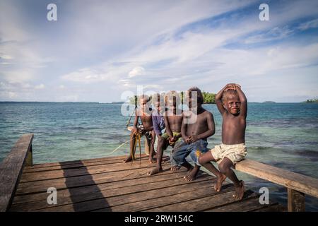 Chea Vilalge, Salomonen, 15. Juni 2015: Gruppe von Kindern, die auf einem hölzernen Pier sitzen Stockfoto