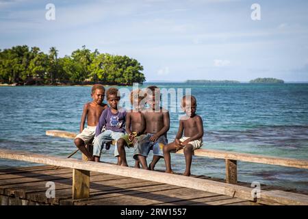 Chea Vilalge, Salomonen, 15. Juni 2015: Gruppe von Kindern, die auf einem hölzernen Pier sitzen Stockfoto