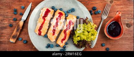 Gebackener Lachsfisch mit Heidelbeersauce. Lachsfilets, gegrillte Steaks auf einem Holztisch. Draufsicht. Stockfoto