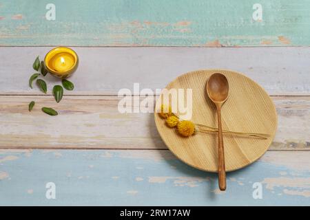 Ein Stillleben mit einigen getrockneten Blumen auf einem Holzteller und einer Kerze in einem kleinen Behälter Stockfoto