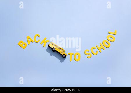Auf gelbem Hintergrund ein gelber Schulbus mit Straßenmarkierungen zurück zur Schule. Konzeptfoto. Stockfoto