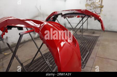 Roter Kunststoff-Autostoßfänger trocknet nach dem Lackieren in der Spritzkabine Stockfoto