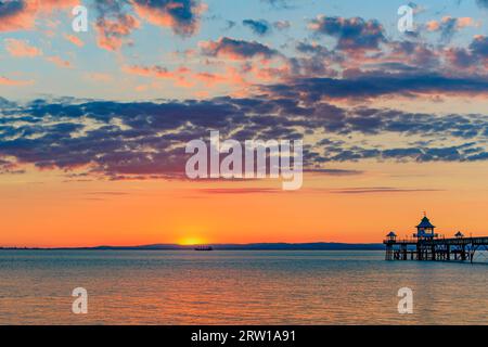 Clevedon Pier an einem hellen und farbenfrohen Abend, während die Sonne über der walisischen Küste untergeht Stockfoto