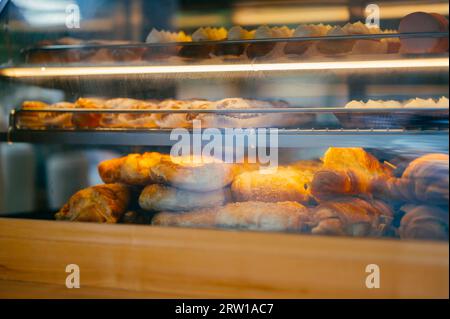 Nahaufnahme von frisch gebackenen Croissants und anderen leckeren Gebäckstücken in einem Ladenregal. Stockfoto