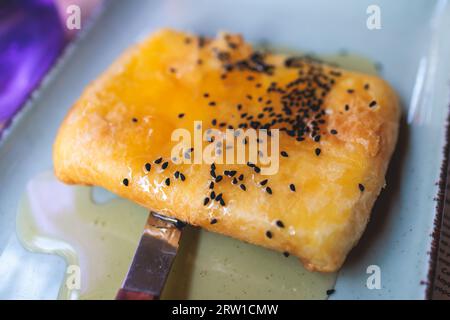 Gebratener Fetakäse in Phyllo-Gebäck mit Honig und Sesam, traditioneller griechischer Vorspeise auf einem Teller, serviert in einer traditionellen Taverna-Café-Pause Stockfoto