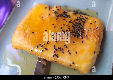 Gebratener Fetakäse in Phyllo-Gebäck mit Honig und Sesam, traditioneller griechischer Vorspeise auf einem Teller, serviert in einer traditionellen Taverna-Café-Pause Stockfoto