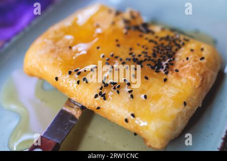 Gebratener Fetakäse in Phyllo-Gebäck mit Honig und Sesam, traditioneller griechischer Vorspeise auf einem Teller, serviert in einer traditionellen Taverna-Café-Pause Stockfoto