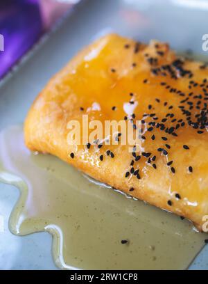 Gebratener Fetakäse in Phyllo-Gebäck mit Honig und Sesam, traditioneller griechischer Vorspeise auf einem Teller, serviert in einer traditionellen Taverna-Café-Pause Stockfoto