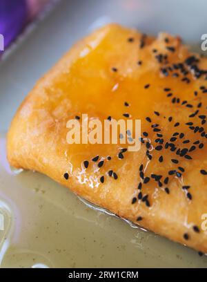 Gebratener Fetakäse in Phyllo-Gebäck mit Honig und Sesam, traditioneller griechischer Vorspeise auf einem Teller, serviert in einer traditionellen Taverna-Café-Pause Stockfoto