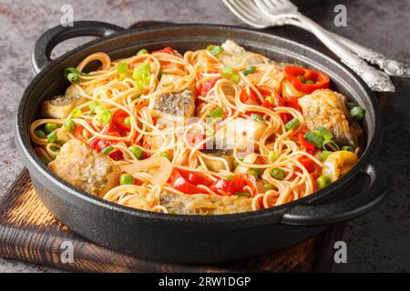 Mediterrane Spaghetti mit weißem Meeresfisch, Gemüse und Tomatensauce aus nächster Nähe in einer Pfanne auf dem Tisch. Horizontal Stockfoto