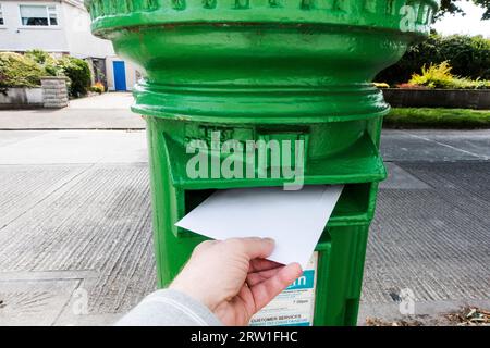 Mans händisch einen Brief in einem irischen Briefkasten posten Stockfoto