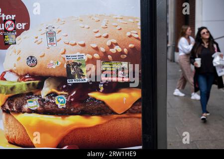 Tierrechte und pro-vegane Protestaufkleber auf einem Werbeplakat für einen McDonalds Beef Burger am 14. August 2023 in London, Großbritannien. Stockfoto