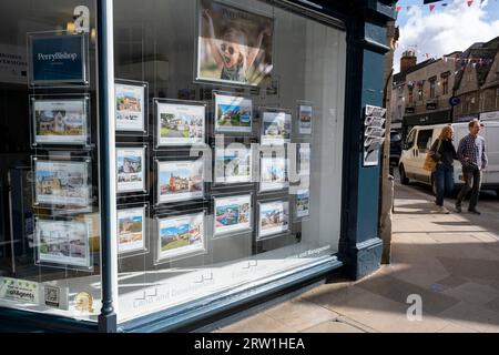 Am 13. September 2023 in Cirencester, Großbritannien, kommen die Leute an Häusern vorbei, die in einem Fenster für Immobilienmakler verkauft werden. Cirencester ist bekannt dafür, dass es in seinem kleinen Stadtzentrum eine große Anzahl von Immobilienmaklern gibt, da der ländliche Wohnungsmarkt weiterhin aktiv ist. Cirencester ist eine Marktgemeinde in Gloucestershire. Es ist die achtgrößte Siedlung in Gloucestershire und die größte Stadt innerhalb der Cotswolds. Die meisten Gebäude und Häuser in der Stadt sind aus dem charakteristischen honigfarbenen Cotswold Stone gefertigt. Stockfoto