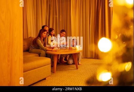 Silvesterfeier mit der Familie. Vater, Mutter und drei Töchter haben Spaß mit Brettspiel am Heiligabend. Eltern und ihre süßen Mädchen sind p Stockfoto