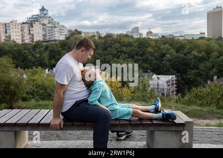 Vater und Sohn spazierten durch die Stadt und setzten sich auf eine Bank, um sich zu entspannen und zu unterhalten. Familienzeit für die männliche Hälfte, glückliche Vaterschaft, Kindheit. Vater Stockfoto