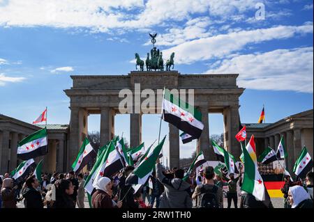 18.03.2023, Deutschland, Berlin, Berlin - Europa - bei einer pro-syrischen Kundgebung auf dem Pariser Platz vor dem Brandenburger Tor schwenken Menschen syrische Flaggen Stockfoto