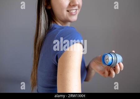 Nahaufnahme eines Mädchens, das vor dem Aufkleben auf den Arm den Halter für das Flash-Glucose-Monitoring-Pflaster hält Stockfoto