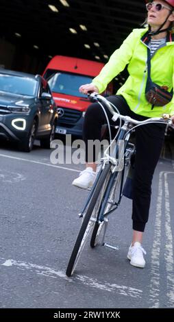 Vertikale Ansicht Frau Radfahrerin Fahrrad fahrend Fahrrad auf der Straße im Beech Street Tunnel Verkehr für Lichter zu wechseln London E2 UK KATHY DEWITT Stockfoto