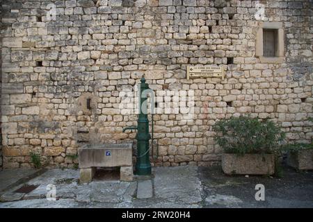 Ein alter Brunnen vor einer Steinmauer. Stockfoto