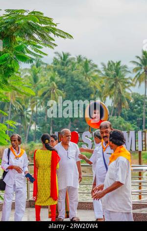 Puttaparthi, Indien - 1. September 2023: Sai Baba-Anhänger in weiß gekleidet mit gelbem Schiefer stehen am See in Puttaparthi, vertikal Stockfoto