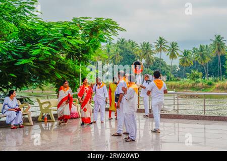 Puttaparthi, Indien - 1. September 2023: Sai Baba-Anhänger in weiß gekleidet mit gelbem Schiefer stehen am See in Puttaparthi Stockfoto