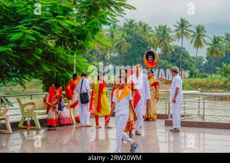 Puttaparthi, Indien - 1. September 2023: Sai Baba-Anhänger in weiß gekleidet mit gelbem Schiefer stehen am See in Puttaparthi Stockfoto