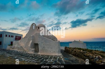 Traditionelle weiße griechische Kirche in der Nähe des Meeres auf Mykonos Insel bei Sonnenuntergang Stockfoto