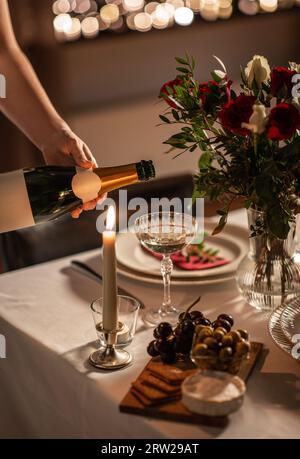 Champagner wird von der Flasche zum Glas auf dem Tisch gegossen Stockfoto