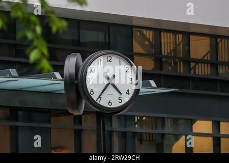 Doppelseitige Bahnhofsuhr mit ca. 5:35, die häufig in Verkehrsknotenpunkten, Bahnhöfen und modernen öffentlichen Räumen zu sehen ist. Stockfoto
