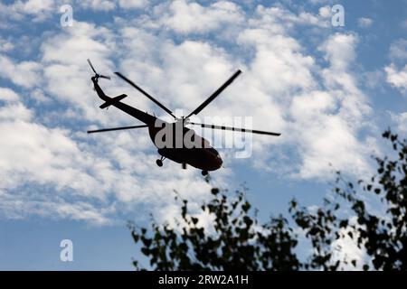 Die Silhouette des Mi-8-Hubschraubers vor dem blauen Himmel mit Wolken im Flug. Stockfoto