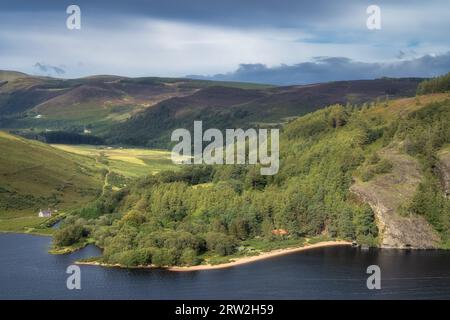 Wunderschönes Luftpanorama mit Häusern, See, Sandstrand, grünem Wald und Bergen. Lough Dan in Wicklow Mountains, Irland Stockfoto