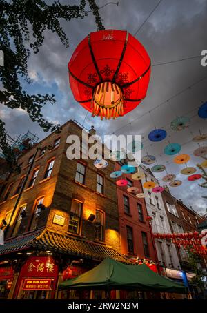London, UK: Kreuzung von Gerard Street und Macclesfield Street in Londons Chinatown. Rote chinesische Laternen und bunte Sonnenschirme hängen über der Straße. Stockfoto