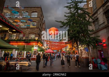 London, UK: Kreuzung von Gerard Street und Macclesfield Street in Londons Chinatown. Rote chinesische Laternen und bunte Sonnenschirme hängen über der Straße. Stockfoto