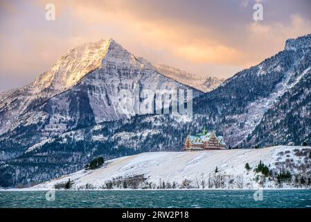 Das Prince of Wales Hotel liegt auf einem Vorgebirge mit Blick auf den Upper Waterton Lake, mit Bertha Peak im Hintergrund, an einem stürmischen Wintermorgen Stockfoto