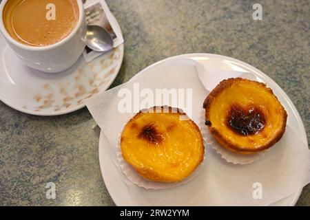 Zwei traditionelle portugiesische Eierkuchen, Pastel de Nata, mit einer Tasse Kaffee Stockfoto