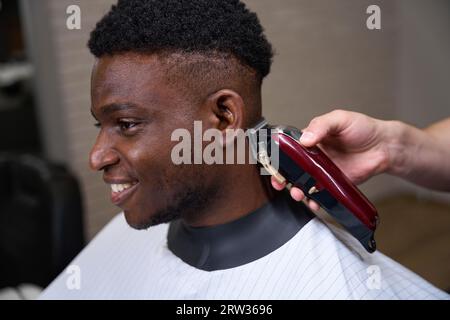 Der junge Afroamerikaner bekommt einen Haarschnitt in einem Friseurladen Stockfoto