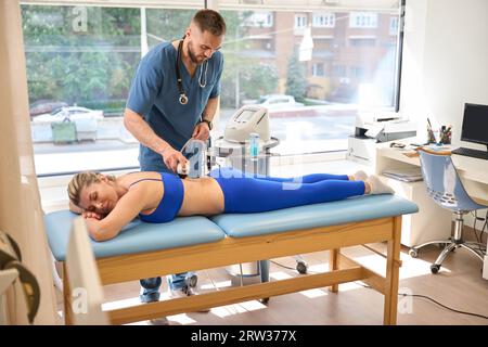 Rehabilitologiespezialist mit extrakorporaler Stosswellentherapie Stockfoto